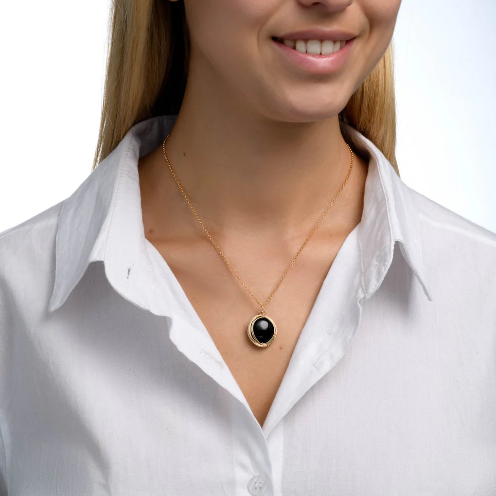 Universe Coin Onyx Necklace featuring a natural coin-shaped black onyx set in a gold-filled spiral pendant